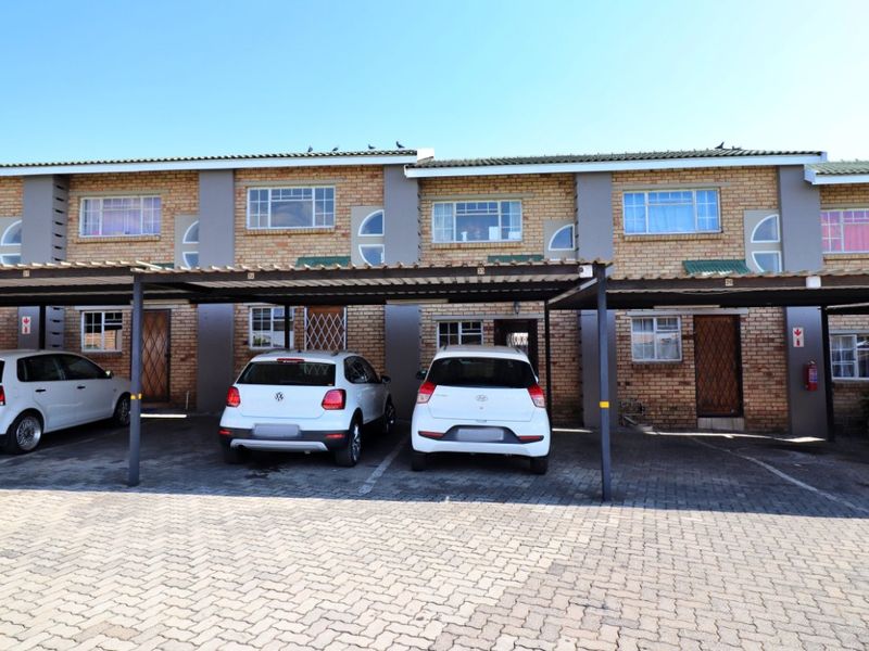Exterior view of a multi-unit apartment complex featuring face-brick facades and dedicated covered parking bays for residents.