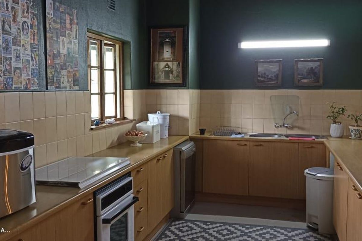 A functional kitchen featuring wooden cabinetry, tiled splashbacks, and a double-basin sink, offering a practical layout for daily meal preparation.