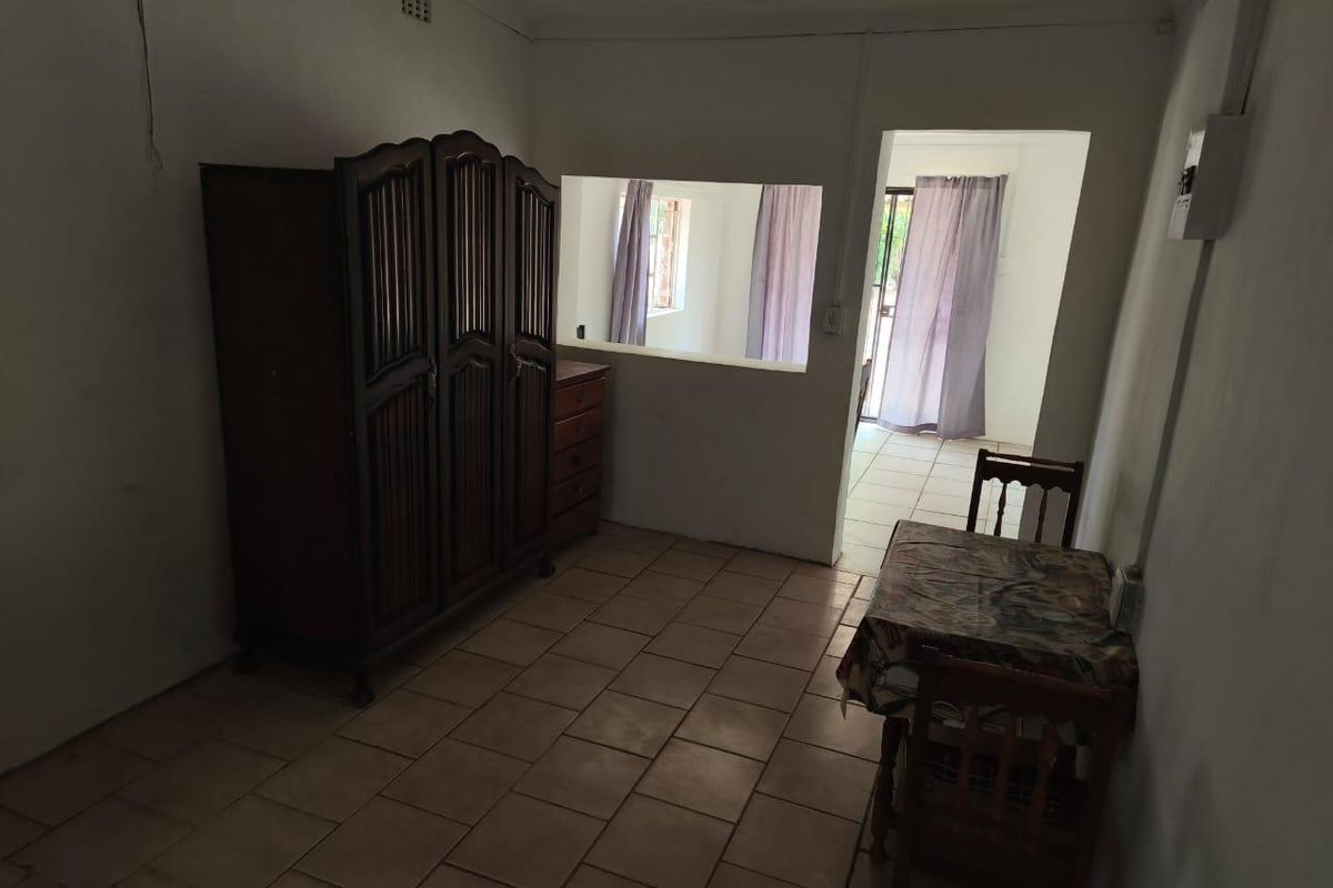 A living area featuring ceramic floor tiles, an internal service window, and access to an adjacent room.