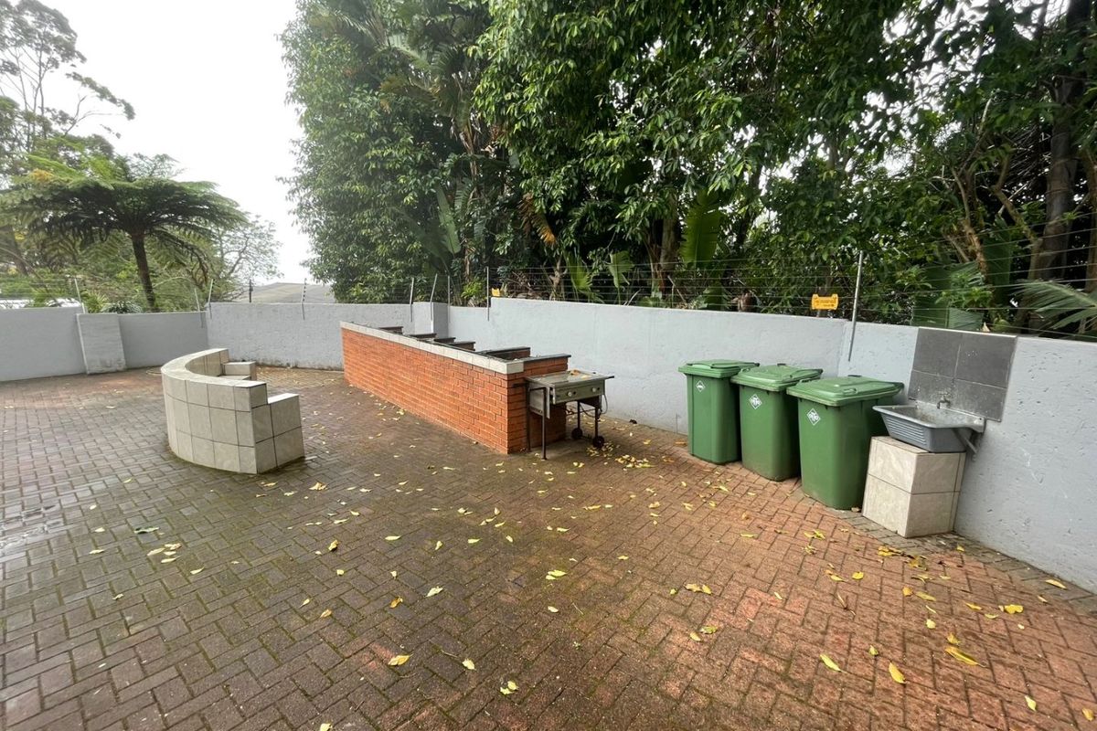 Outdoor entertainment area featuring a brick-built barbecue station, tiled seating, and a utility sink set against a perimeter wall.