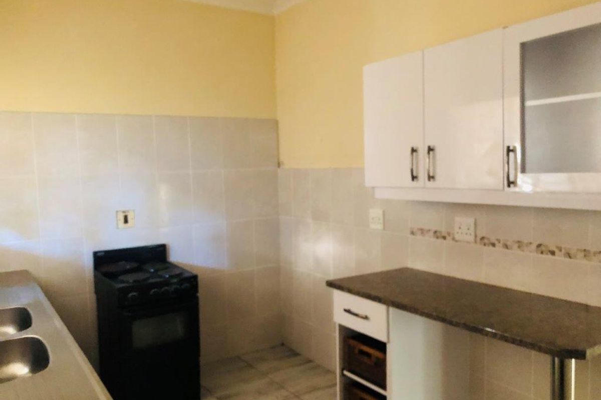 A functional kitchen featuring built-in cabinetry, a freestanding stove, and tiled splashbacks, offering a practical layout for daily meal preparation.