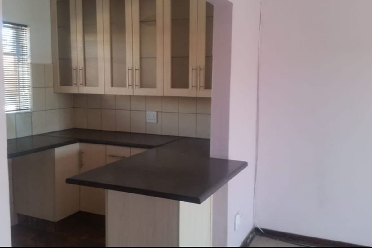 A functional kitchen featuring light-toned built-in cabinetry, dark laminate countertops, a tiled backsplash, and a convenient breakfast bar area.