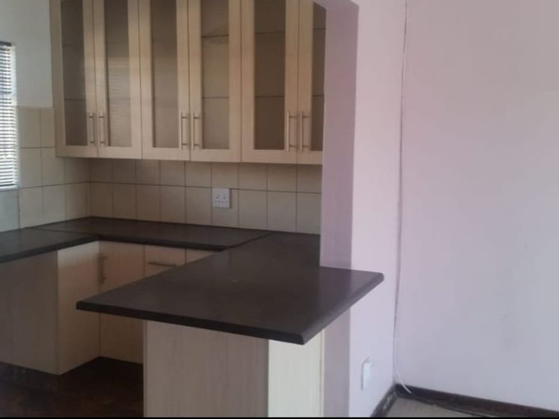 A functional kitchen featuring light-toned built-in cabinetry, dark laminate countertops, a tiled backsplash, and a convenient breakfast bar area.