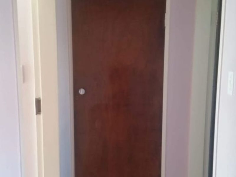 A functional hallway featuring tiled flooring and a built-in storage cupboard with overhead cabinet space.