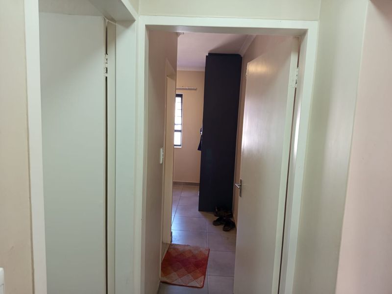 A functional hallway connecting interior spaces, featuring tiled flooring and a built-in cupboard.