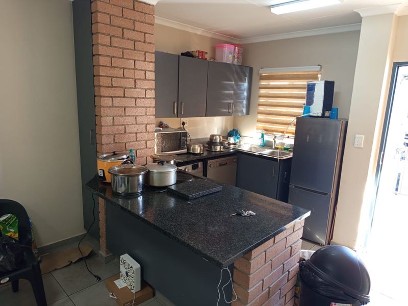 A functional kitchen featuring dark cabinetry, granite countertops, and an exposed brick breakfast bar, providing a practical layout for daily meal preparation.