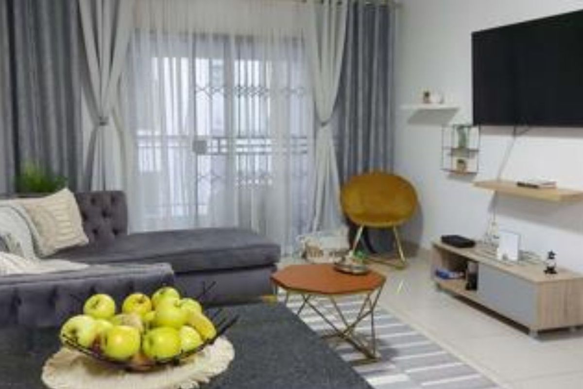 A comfortable living room featuring tiled flooring and a sliding glass door with a security gate, providing access to the outdoor area.