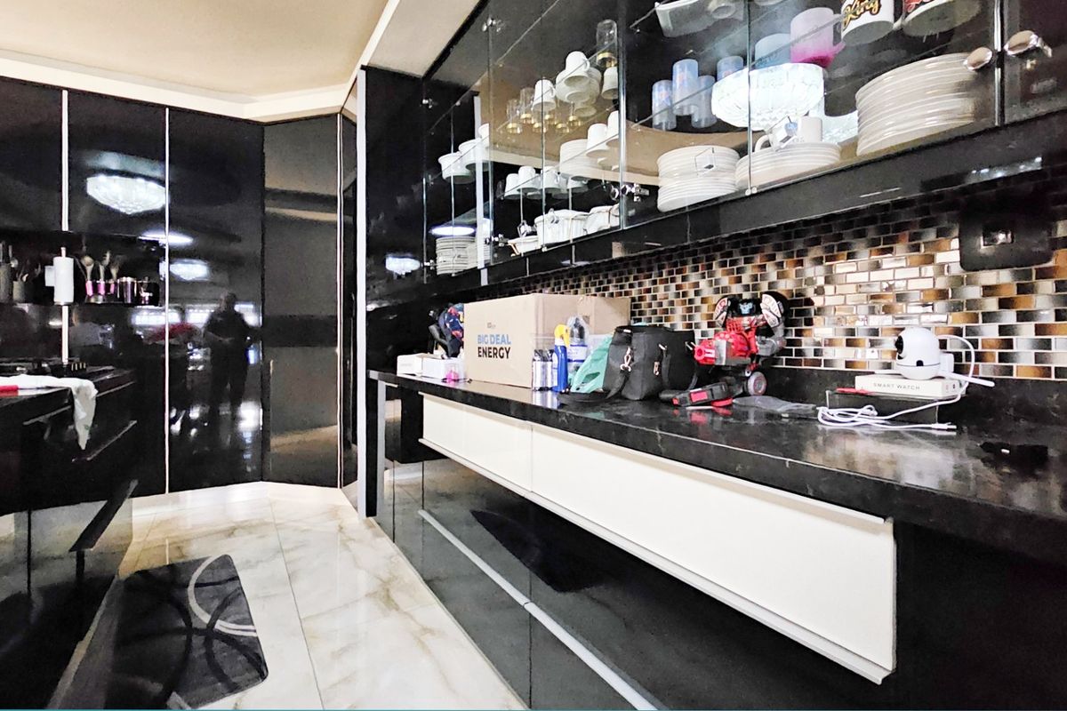 Modern kitchen featuring high-gloss black cabinetry, stone countertops, and a decorative mosaic tile backsplash with integrated glass-front display storage.