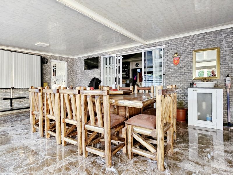 A spacious covered patio featuring marble-look tiled flooring, brick-style wall cladding, and integrated sliding doors, providing a versatile outdoor entertainment area.