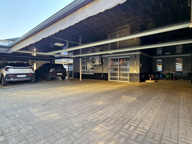 Spacious covered parking area featuring paved flooring, a retractable awning, and secure access points, providing ample space for multiple vehicles.