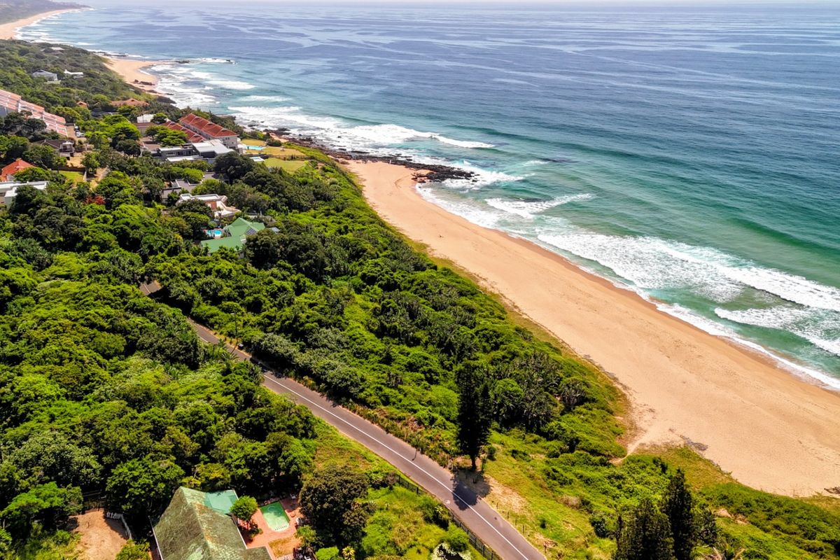 An aerial view of the coastal residential area, showcasing the proximity to the beach, surrounding natural vegetation, and local road infrastructure.