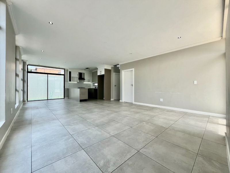 Spacious open-plan living area featuring large format floor tiles, recessed lighting, and a modern kitchen with built-in cabinetry and a functional island.