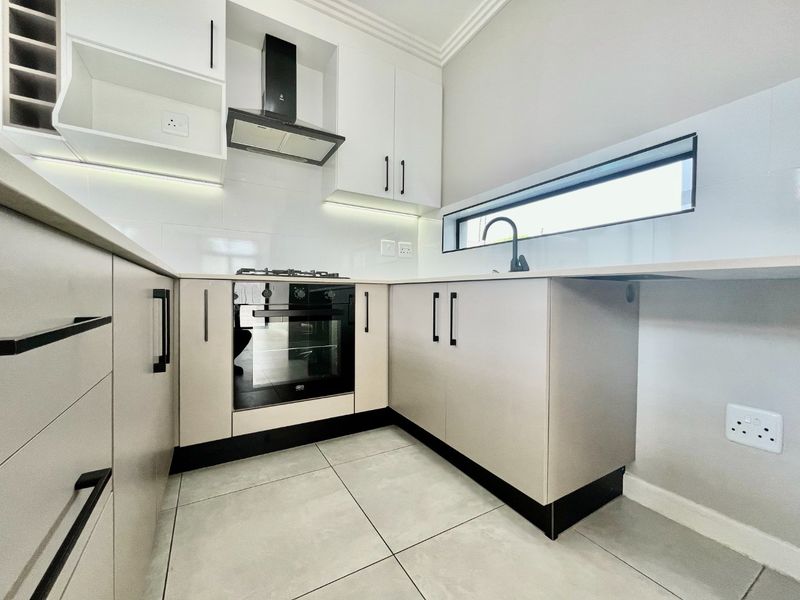 Modern kitchen featuring sleek cabinetry, built-in oven and gas hob, tiled flooring, and contemporary finishes with integrated under-cabinet lighting.
