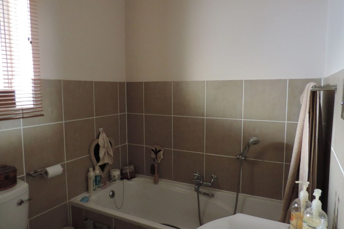 A functional bathroom featuring a bathtub with a shower mixer, tiled walls, and a toilet, providing a neutral and practical space.