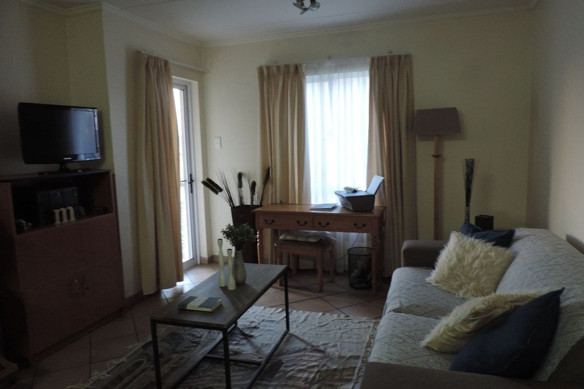 A living room featuring tiled flooring and a glass sliding door providing access to the exterior.