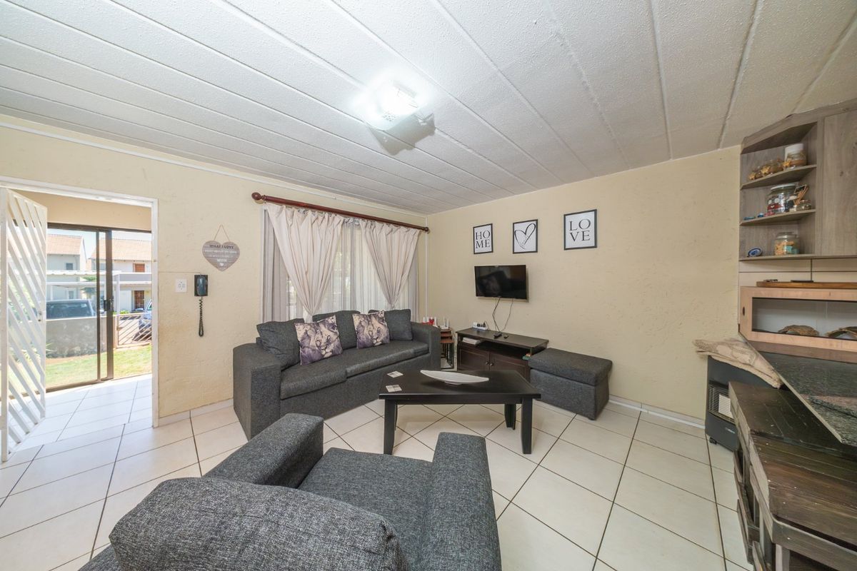 A living room featuring tiled flooring, a textured ceiling, and a sliding door providing access to the exterior.