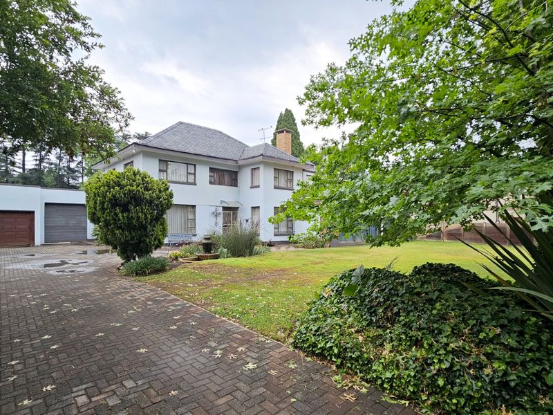 A well-maintained two-story residential property featuring a paved driveway, double garage, and established garden surroundings.