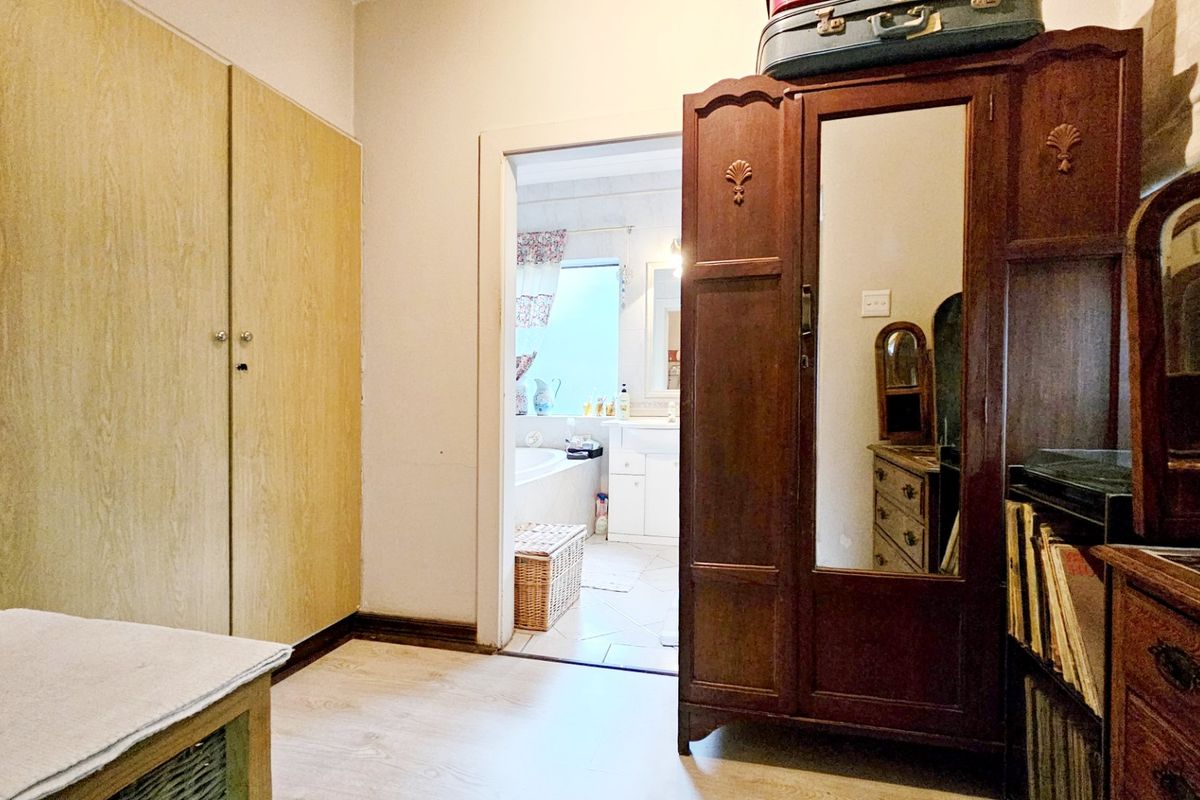 A bedroom featuring built-in wardrobes and laminate flooring, with a direct view into an adjoining bathroom.