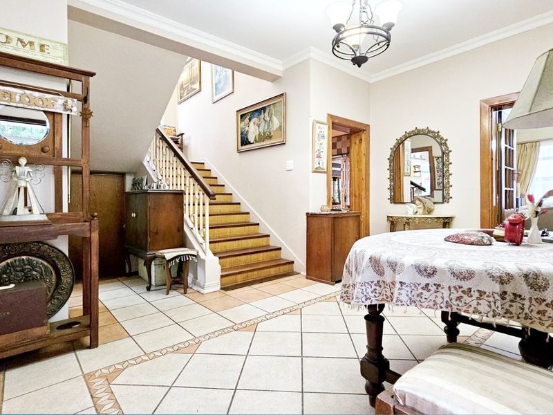 Spacious entrance hall featuring tiled flooring and a wooden staircase, providing a welcoming transition area within the home.
