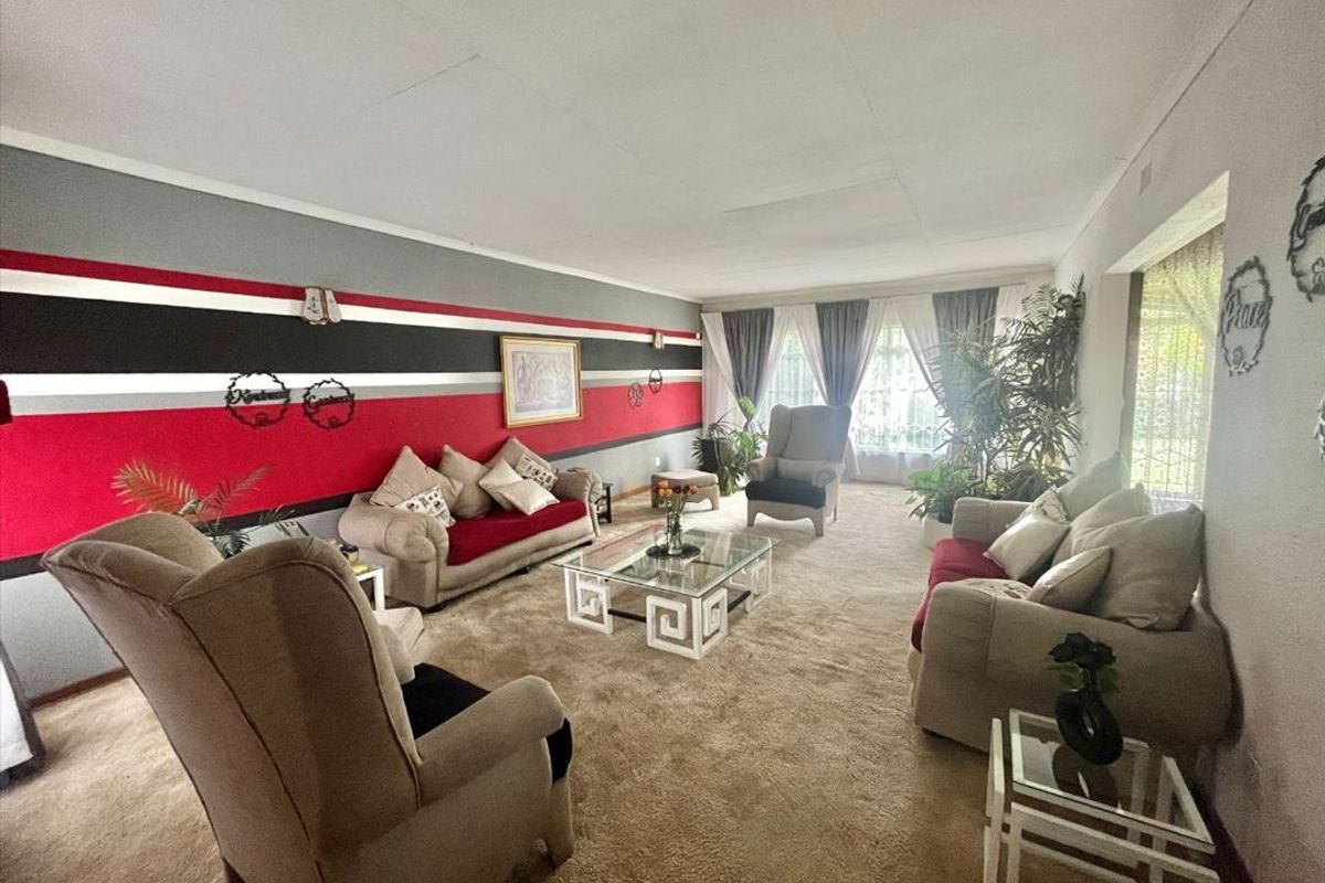 Spacious living room featuring carpeted flooring and large windows, providing ample natural light throughout the area.