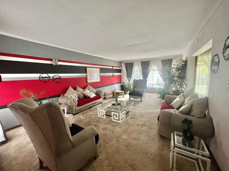 Spacious living room featuring carpeted flooring and large windows, providing ample natural light throughout the area.