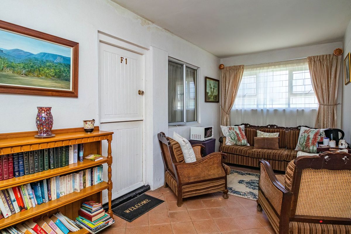 A living room featuring tiled flooring, a stable-style entrance door, and a window with security bars, showing signs of ceiling wear.