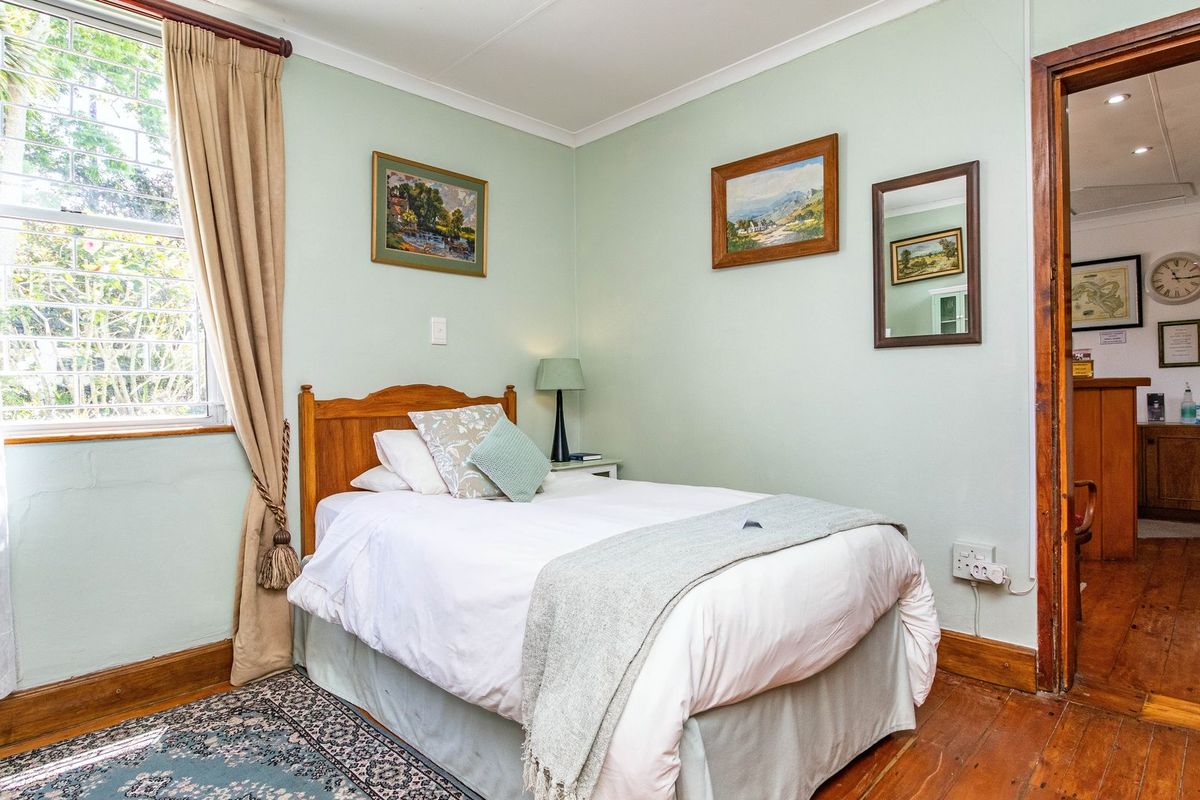 A bedroom featuring timber flooring, coved ceilings, and a window with security bars, providing a functional space with classic architectural details.