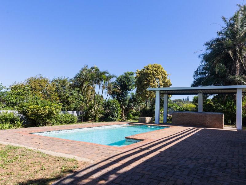 Outdoor pool area featuring a swimming pool, brick paving, and a covered patio with a built-in brick bar counter.