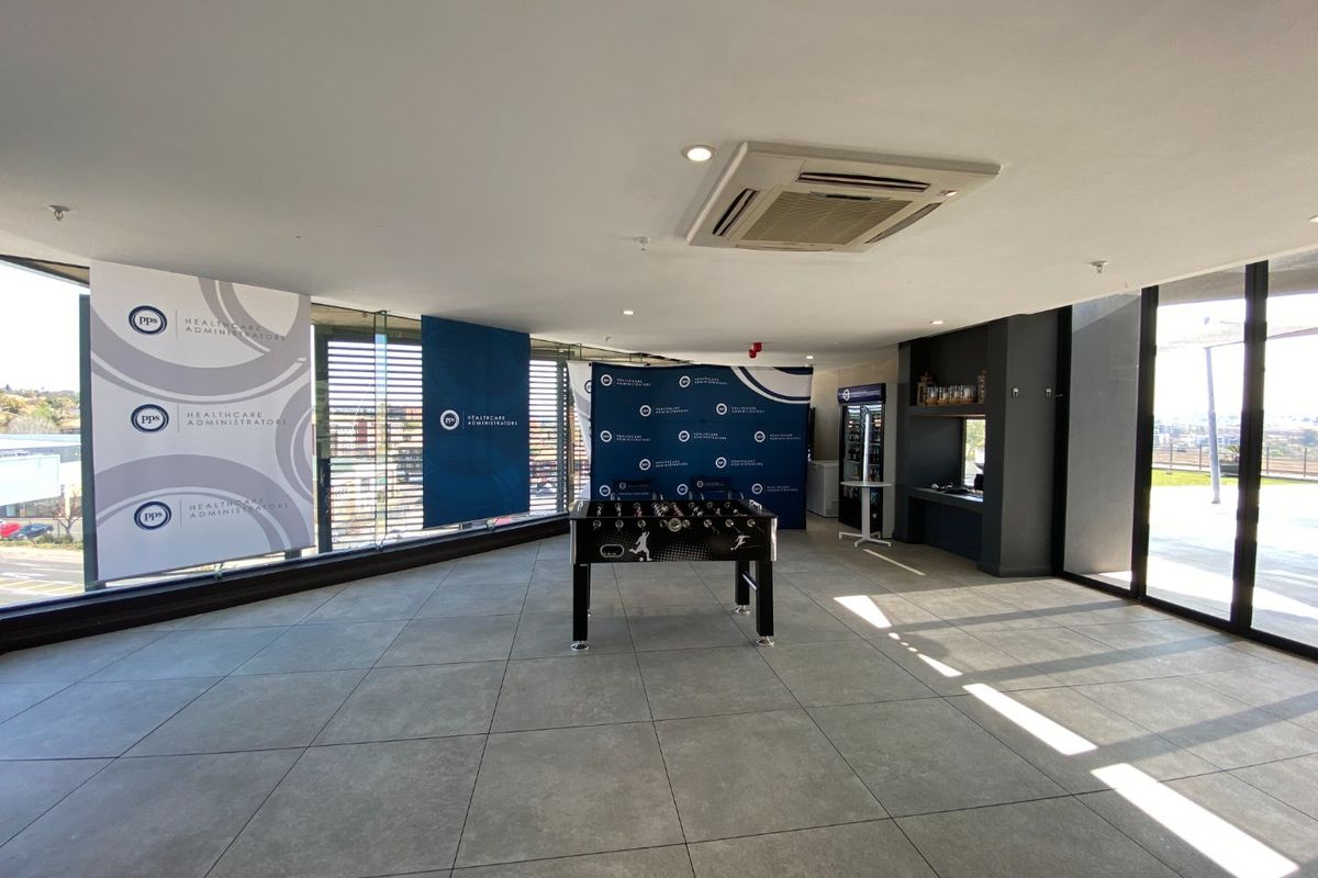 Spacious commercial lounge area featuring large glass windows, tiled flooring, and a built-in ceiling cassette air conditioning unit.