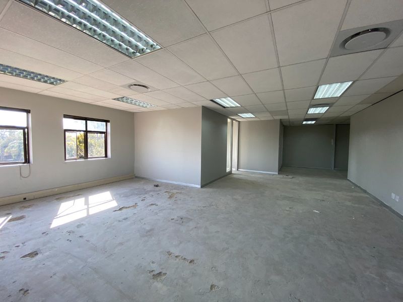 An empty, open-plan commercial office space featuring a suspended ceiling, recessed lighting, and concrete flooring ready for new floor finishes.