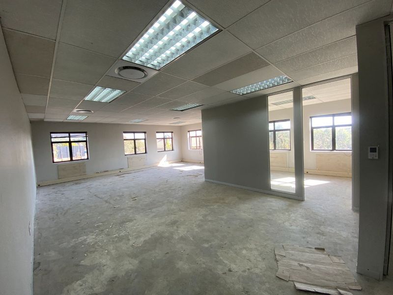 An open-plan commercial office space featuring a suspended ceiling, recessed lighting, and glass partitioning, currently in a shell condition awaiting final flooring and finishes.