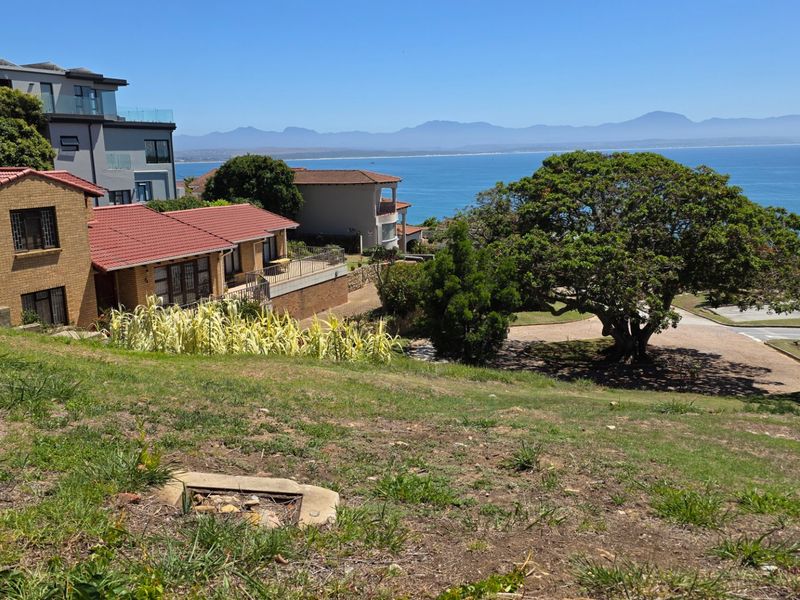 A scenic elevated view overlooking the coastline, ocean, and distant mountains, showcasing the prime location of this residential land.
