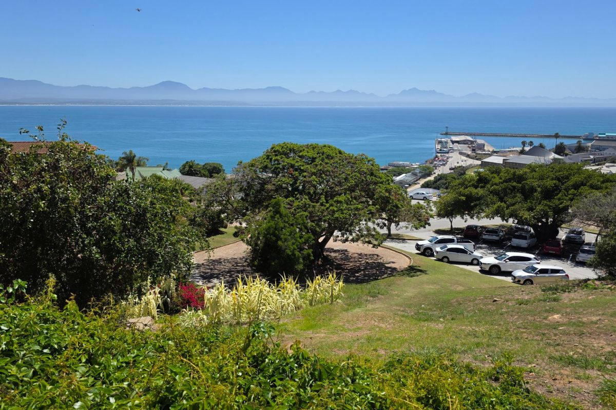 A scenic elevated view overlooking the coastline, harbour, and distant mountain range, showcasing the natural beauty and location of the property.