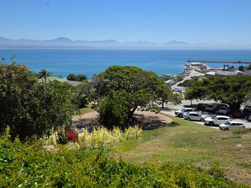 A scenic elevated view overlooking the coastline, harbour, and distant mountain range, showcasing the natural beauty and location of the property.