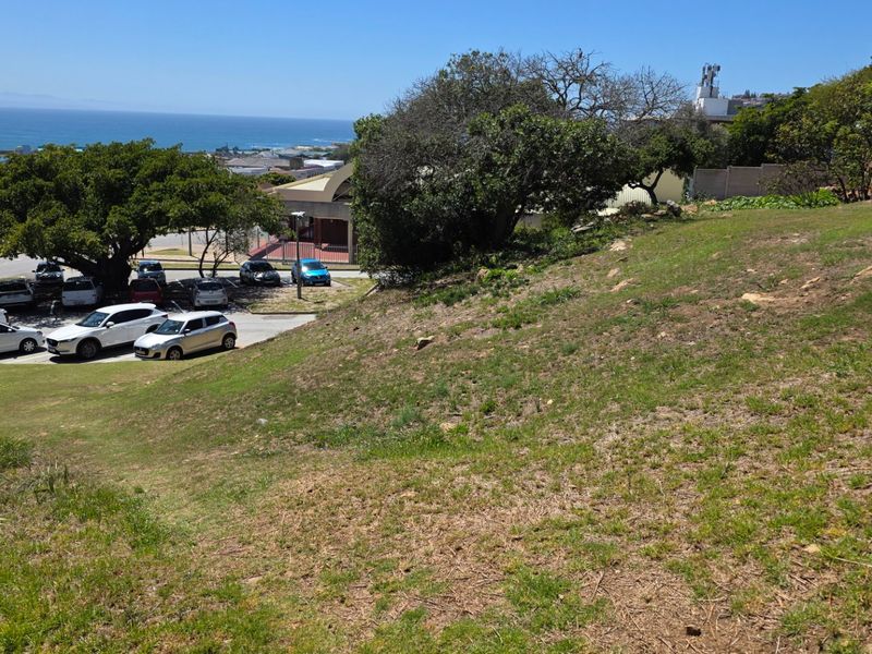 A view of the sloped residential vacant land overlooking the surrounding neighborhood and distant coastline.