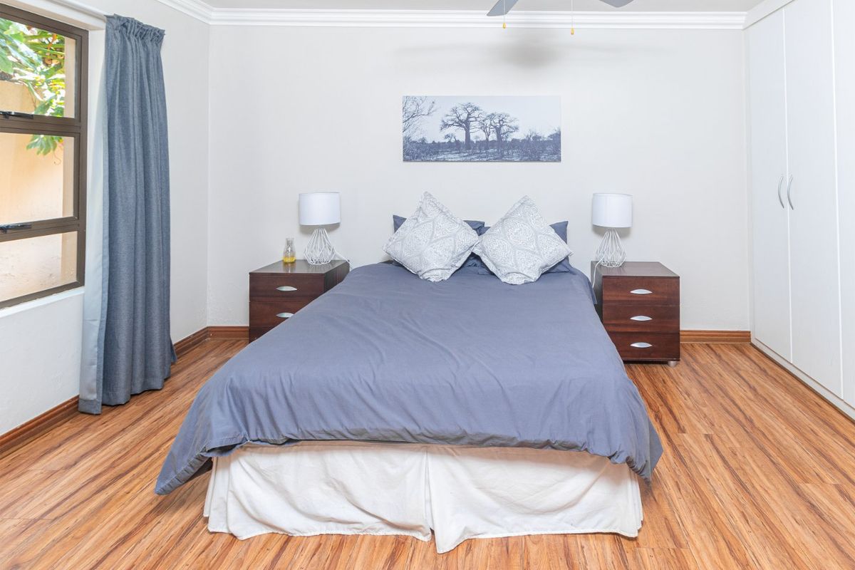 A well-maintained bedroom featuring laminate flooring, a ceiling fan, and built-in cupboards, offering a clean and functional living space.