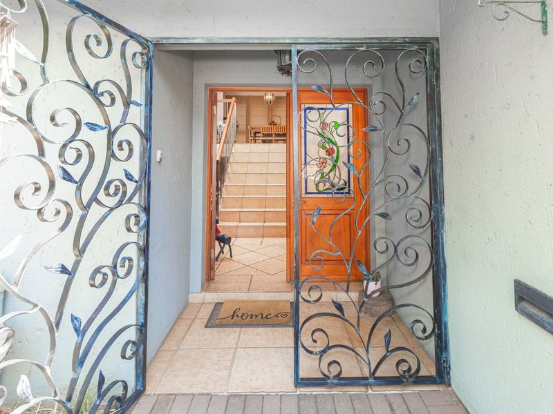 Entrance area featuring a decorative wrought iron security gate and a timber front door with stained glass detailing, leading to an internal staircase.