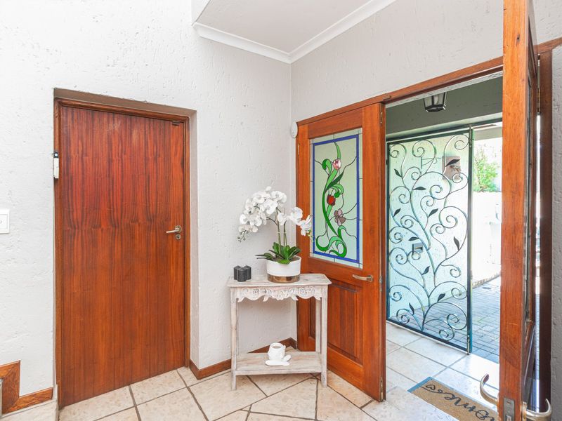 Welcoming entrance hall featuring tiled flooring, a solid wooden door with stained glass detailing, and a decorative wrought iron security gate.