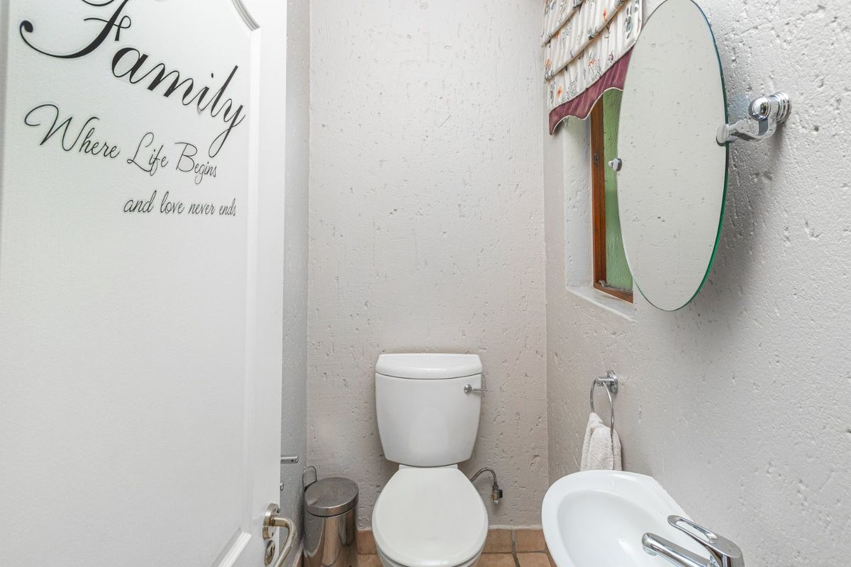 A compact guest bathroom featuring a white toilet, wall-mounted basin with chrome fixtures, and tiled flooring.