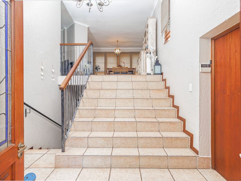 Welcoming entrance hall featuring a tiled staircase with a wrought iron balustrade, leading up to an open-plan living and dining area.