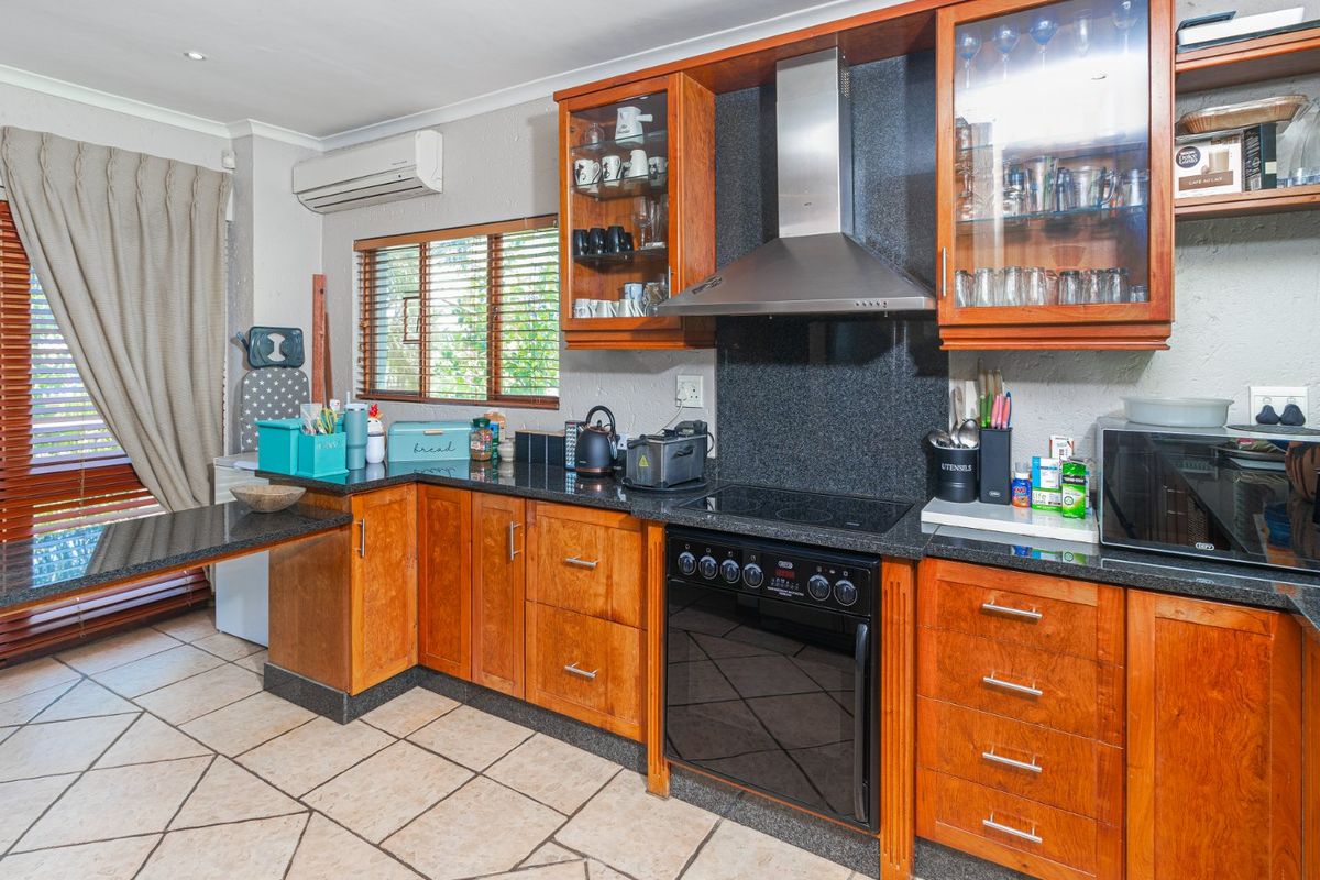 A functional kitchen featuring wooden cabinetry, granite countertops, an integrated electric stove with extractor fan, and tiled flooring.