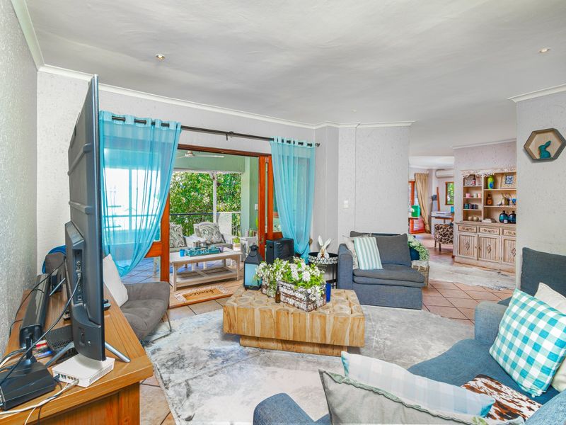 A comfortable living room featuring tiled flooring, recessed lighting, and large sliding glass doors that provide seamless access to the outdoor patio area.