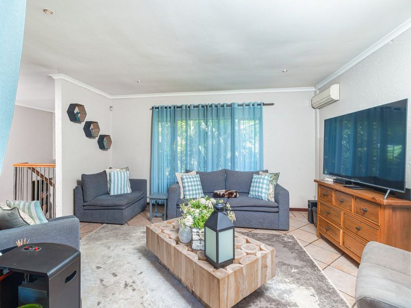 A comfortable living room featuring tiled flooring, recessed lighting, and a wall-mounted air conditioning unit, providing a functional and relaxed space.