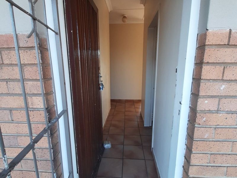 An entry hallway featuring tiled flooring and a security gate, leading into the interior of the commercial property.
