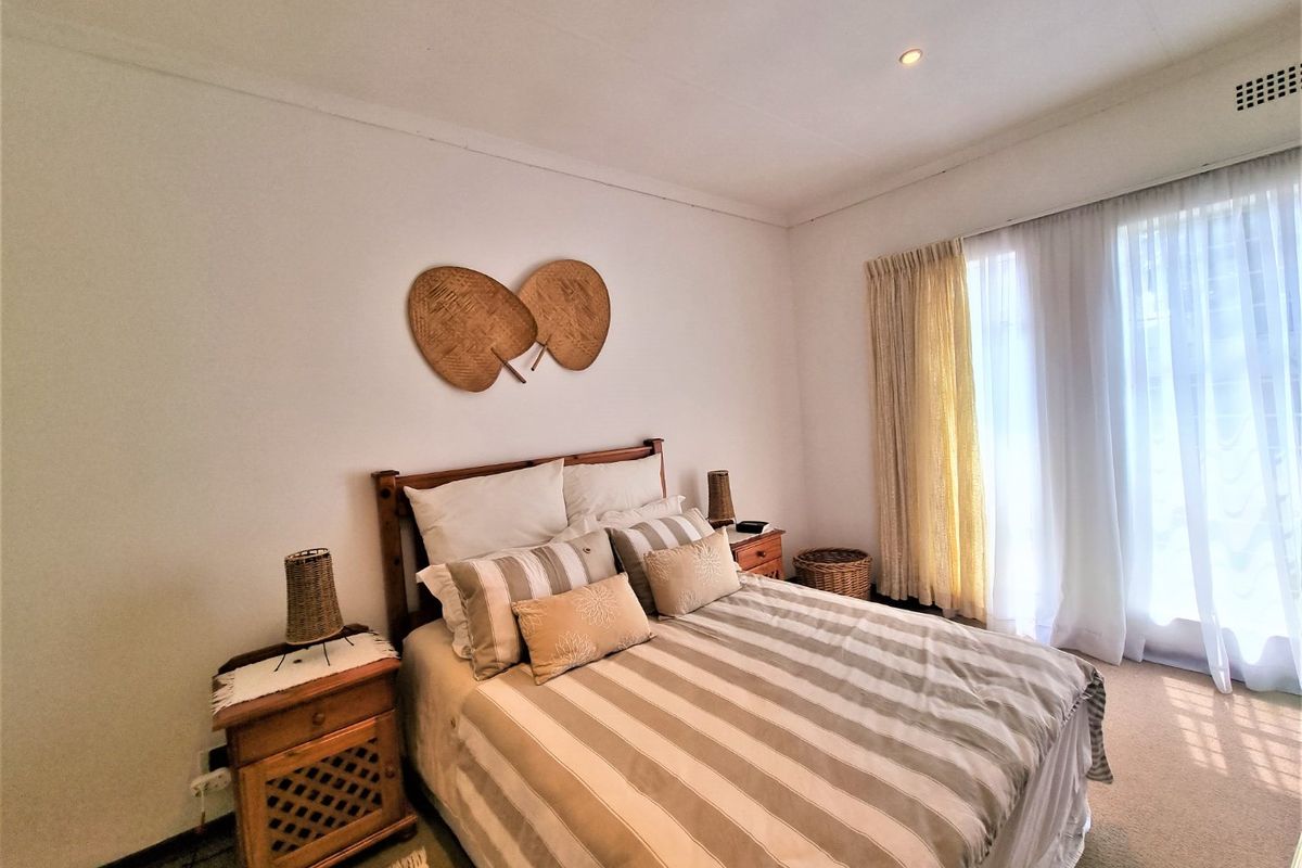 A well-lit bedroom featuring neutral carpet flooring, recessed ceiling lighting, and large windows with installed curtain tracks.