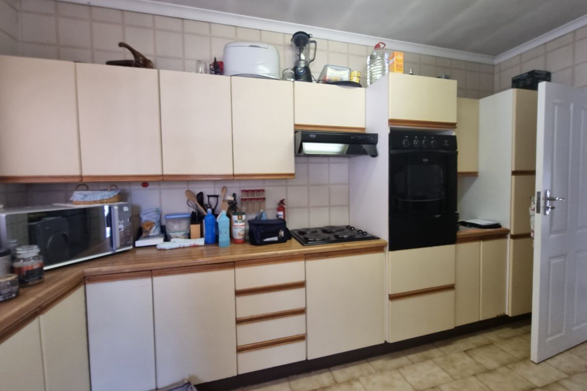 A functional kitchen featuring built-in cabinetry, laminate countertops, a gas hob, extractor fan, and a built-in oven with tiled backsplash and flooring.