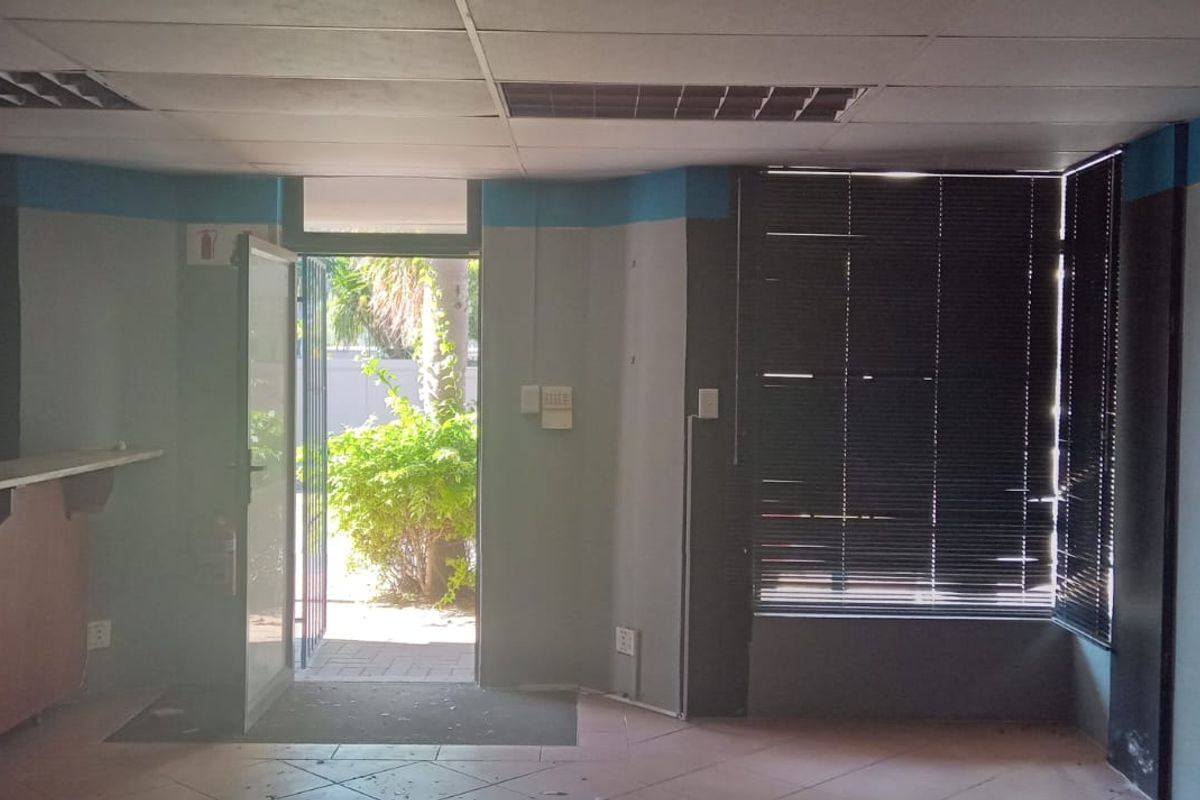 An empty commercial entry area featuring a built-in counter, tiled flooring, drop ceiling, and direct access to an outdoor space.