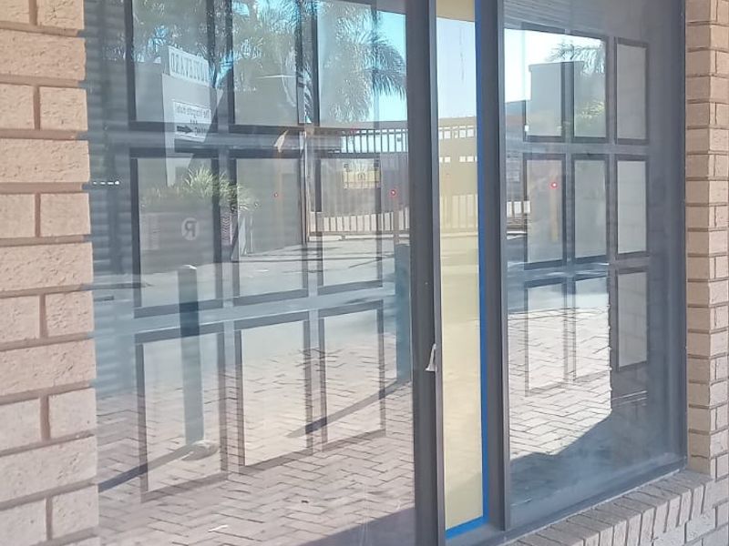 Front exterior view of a commercial property featuring a brick facade and large display windows overlooking a paved walkway.