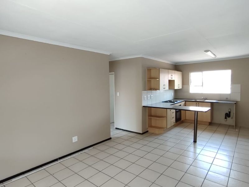 Open-plan living and kitchen area featuring tiled flooring, built-in cabinetry, and a breakfast bar. The space is vacant and ready for renovation.
