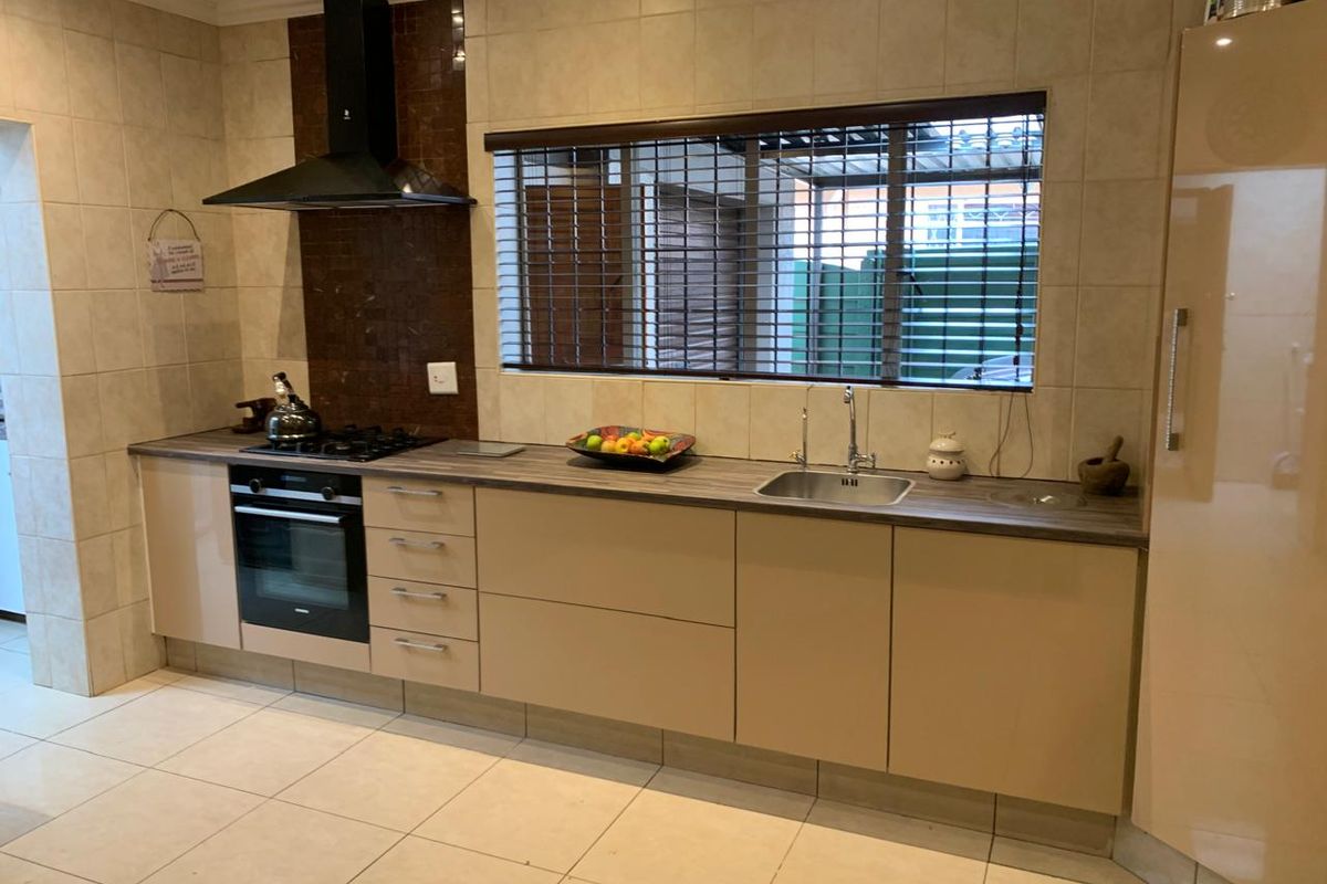 A functional kitchen featuring modern cabinetry, a built-in oven, gas hob, extractor fan, and a stainless steel sink with tiled splashbacks.